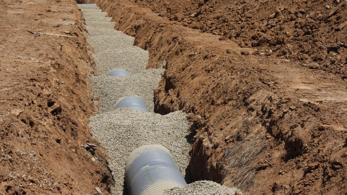 Perforated pipe set in clean gravel during French drain installation in McDonough GA