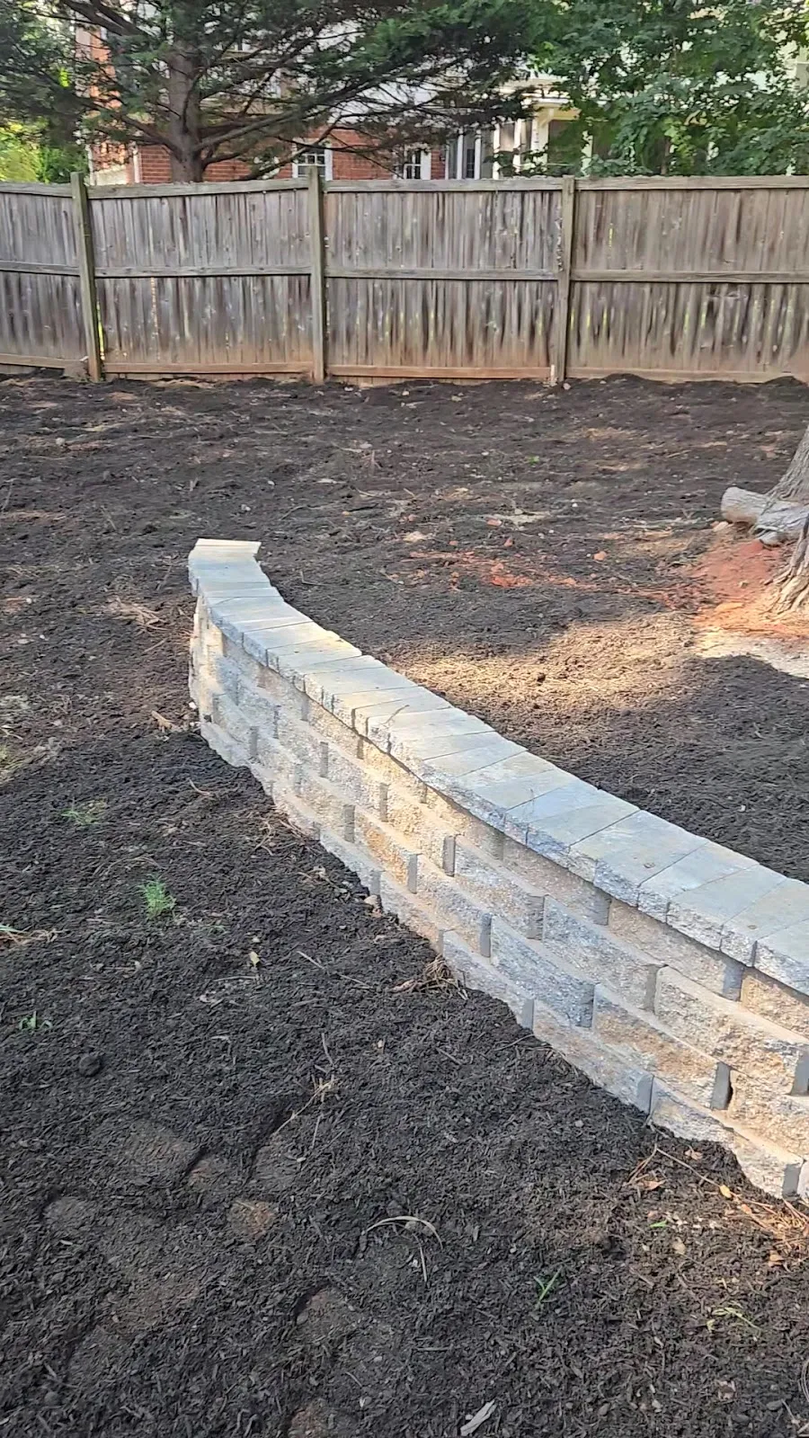 A new block retaining wall holding a freshly graded backyard
