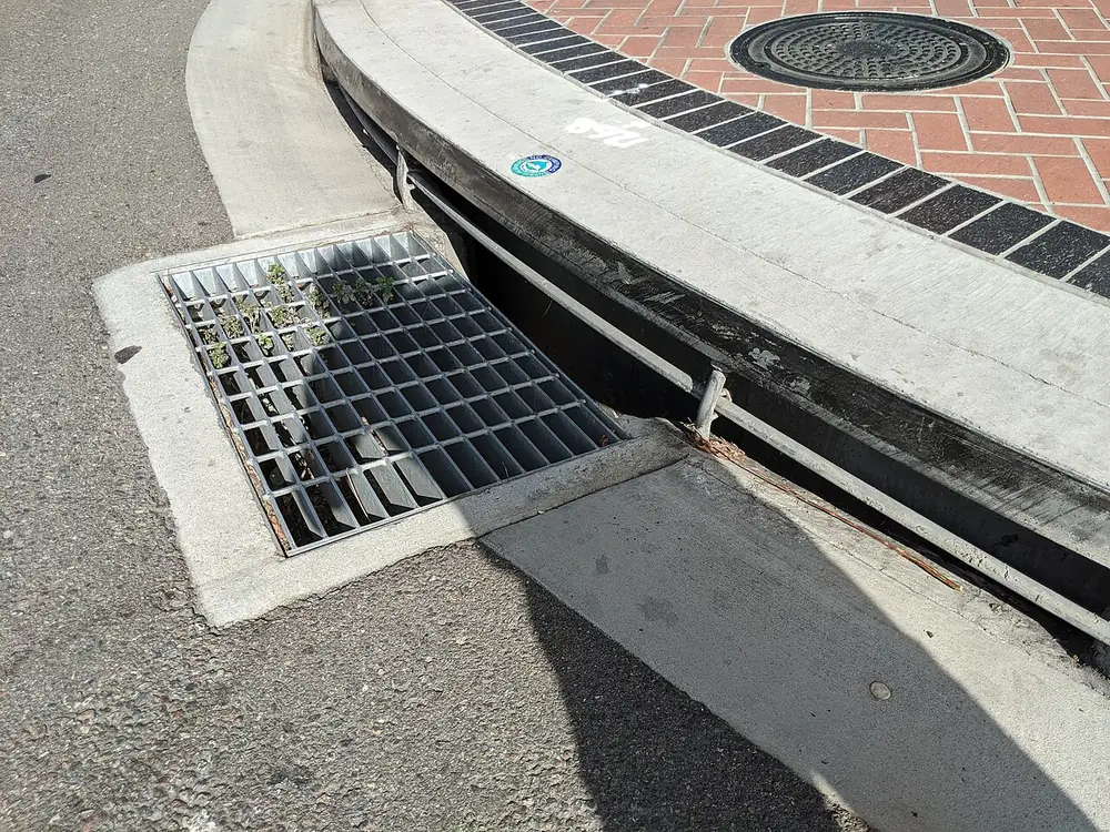 Steel grate and curb opening of a street storm drain inlet