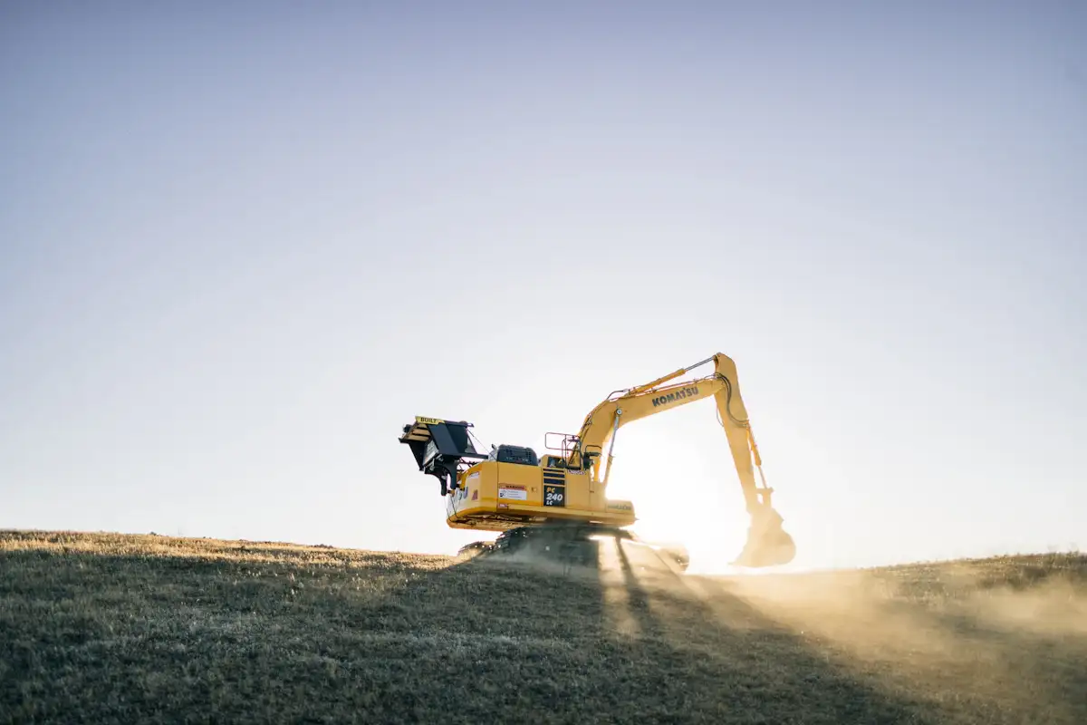 Excavator grading bare soil on an open site, the kind of land disturbance a Henry County drainage permit covers