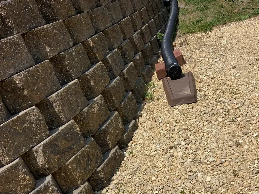 Foundation drain outlet daylighting at the base of a retaining wall in McDonough GA