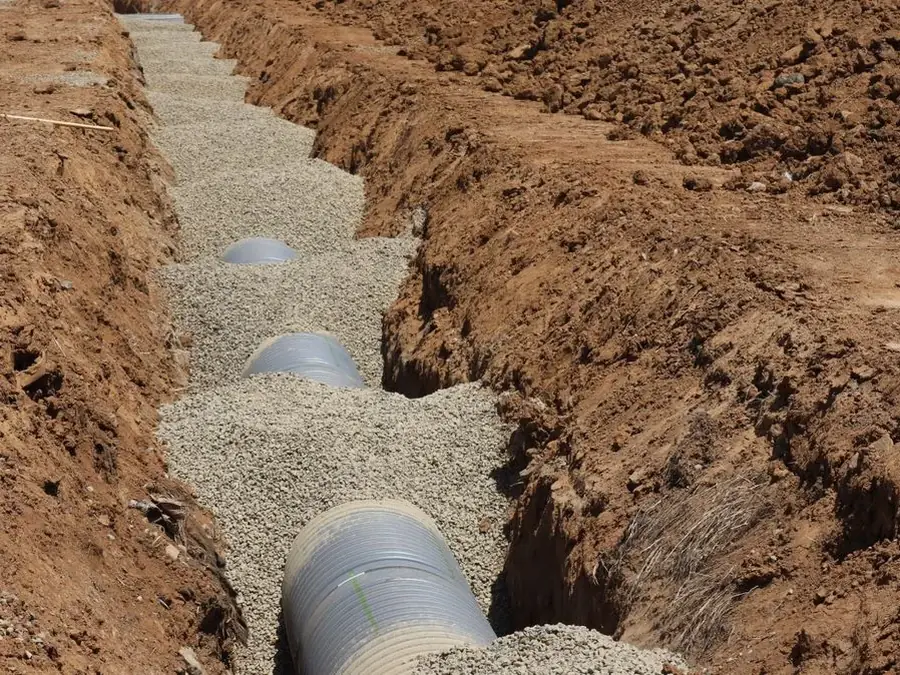 Perforated pipe bedded in clean gravel inside a french drain trench in McDonough GA