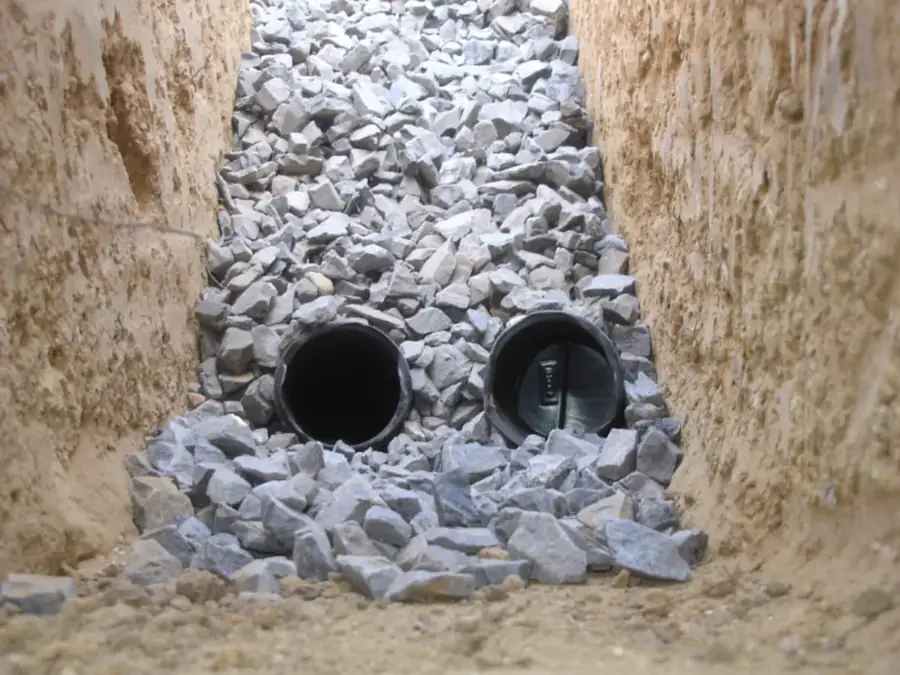 Twin outlet pipes set in gravel for a yard drainage system in McDonough GA
