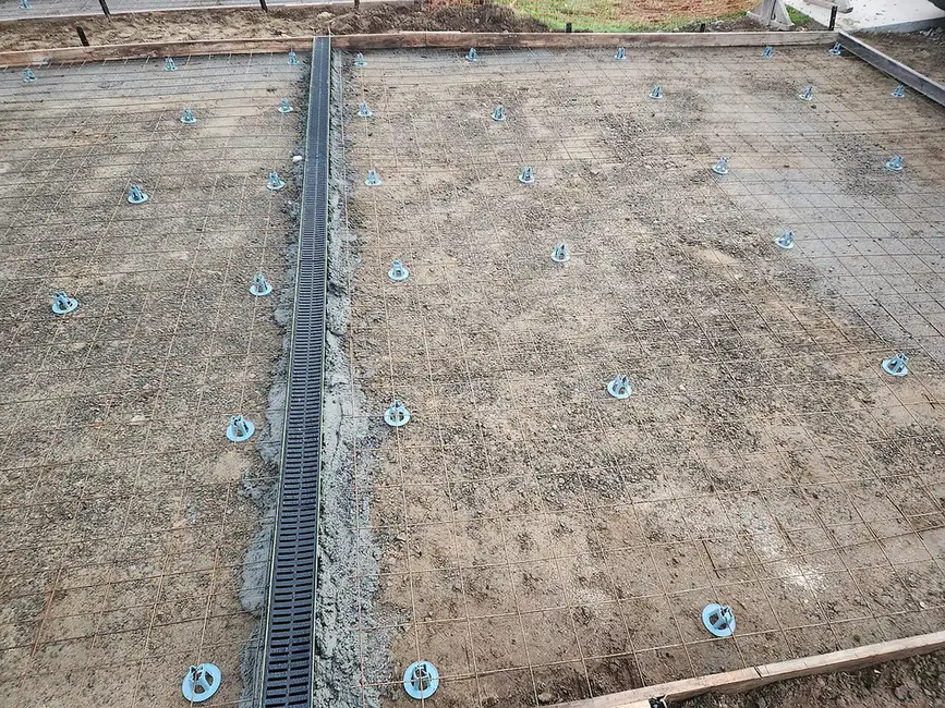 Trench drain installation in a new driveway: channel set between rebar mesh before the concrete pour